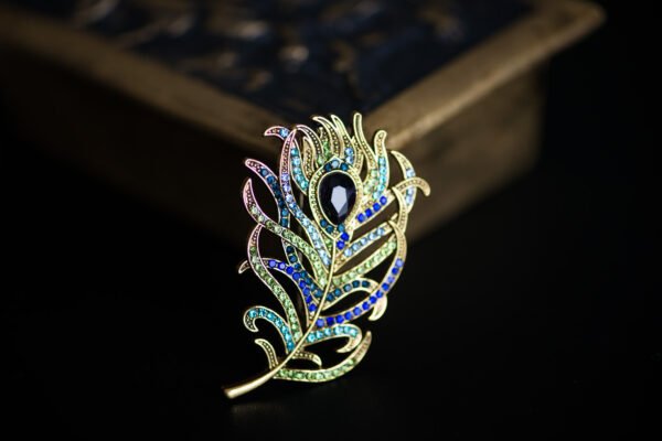 Broche élégante en forme de plume, symbolisant légèreté et liberté, parfaite pour ajouter une touche aérienne à votre tenue.
