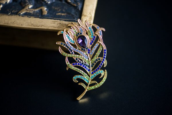 Broche élégante en forme de plume, symbolisant légèreté et liberté, parfaite pour ajouter une touche aérienne à votre tenue.