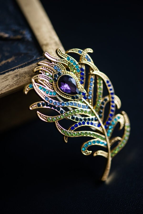 Broche élégante en forme de plume, symbolisant légèreté et liberté, parfaite pour ajouter une touche aérienne à votre tenue.