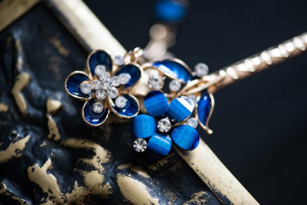 Pic à cheveux orné de fleurs bleues et de strass scintillants, parfait pour apporter une touche de glamour et de couleur à votre coiffure.