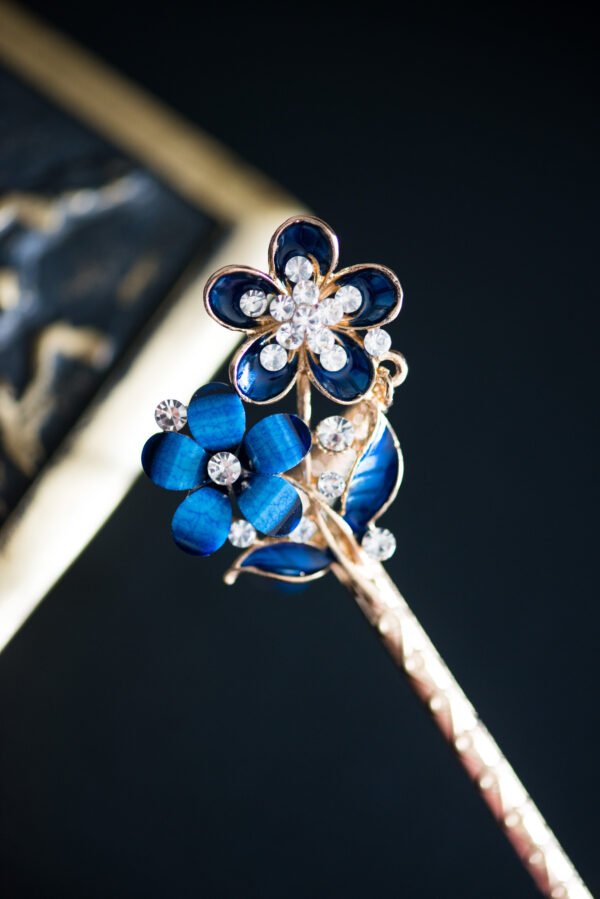 Pic à cheveux orné de fleurs bleues et de strass scintillants, parfait pour apporter une touche de glamour et de couleur à votre coiffure.