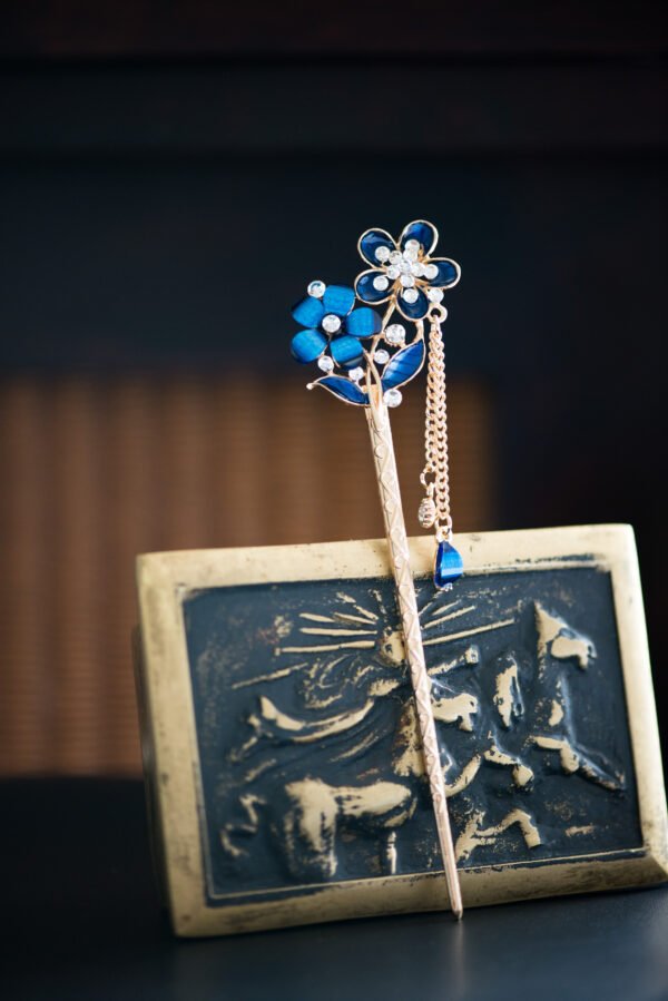 Pic à cheveux orné de fleurs bleues et de strass scintillants, parfait pour apporter une touche de glamour et de couleur à votre coiffure.