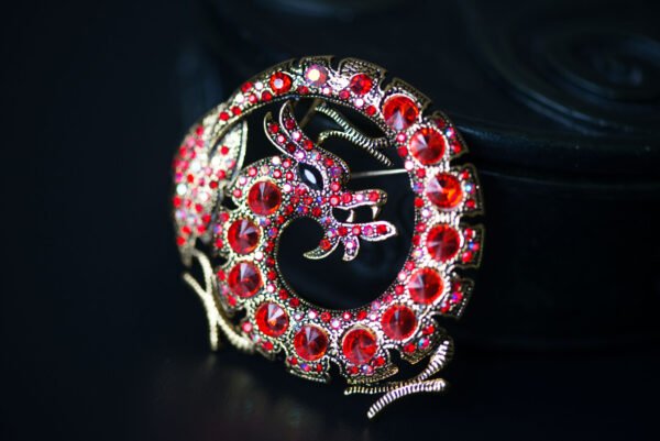 Broche dragon ornée de strass, mesurant 5,3 cm x 2,8 cm. Symbole de puissance et de sagesse, ce bijou élégant brille de mille feux, ajoutant une touche mystique à votre tenue. Léger (30 g) et polyvalent, il s'adapte à toutes les occasions, des événements formels aux sorties décontractées. Un accessoire unique qui évoque les légendes anciennes et affirme votre style audacieux.