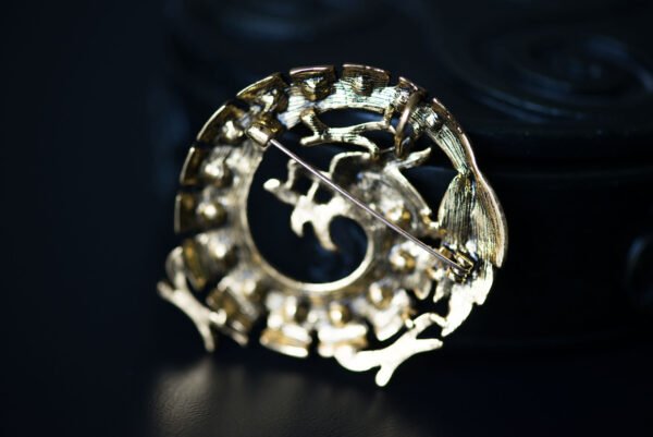 Broche dragon ornée de strass, mesurant 5,3 cm x 2,8 cm. Symbole de puissance et de sagesse, ce bijou élégant brille de mille feux, ajoutant une touche mystique à votre tenue. Léger (30 g) et polyvalent, il s'adapte à toutes les occasions, des événements formels aux sorties décontractées. Un accessoire unique qui évoque les légendes anciennes et affirme votre style audacieux.